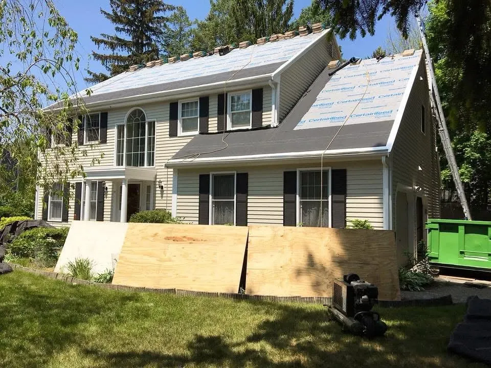 CertainTeed-branded synthetic underlayment rolled across a stripped roof deck, with shingle bundles staged along the ridge